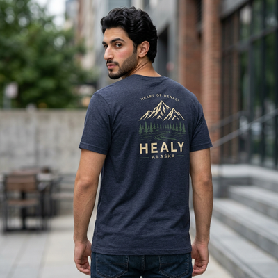 Soft jersey t-shirt with a detailed Healy Alaska mountain and spruce illustration in earthy tones by Evernorth — on model